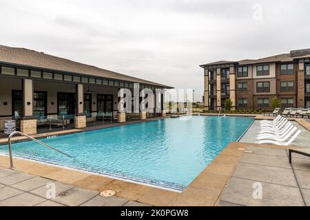 Ruhebereich mit Swimmingpool und Sonnenliegen im Hotel oder Wohnkomplex, Blick auf die Ruhezone mit Pool und Liegestühlen, Gebäude und Himmel Stockfoto