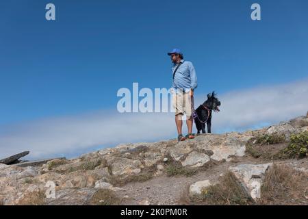 Junger Abenteurer, der mit Hund in der Nähe der Klippe läuft Stockfoto