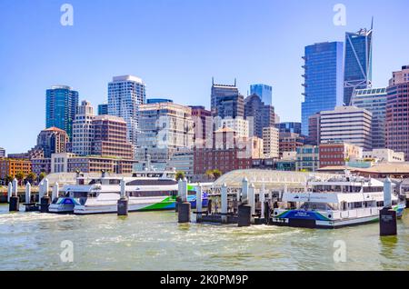 San Francisco Bay Ferries dockten im Hafen der San Francisco Ferry Port mit der Skyline der Stadt dahinter an. Stockfoto