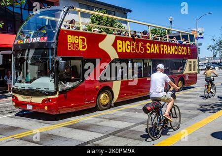 A Big Bus Tours Open-copped Tour Bus in San Francisco, Kalifornien an einem Sommertag, an dem Radfahrer vorbeifahren Stockfoto