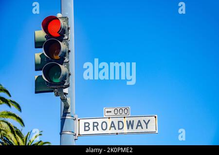 Eine rote Ampel und ein Straßenschild für „Broadway“ vor einem klaren blauen Sommerhimmel in San Francisco, Kalifornien Stockfoto