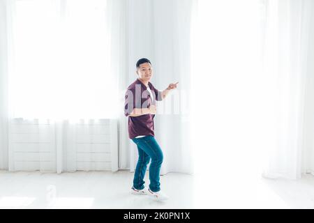 Der asiatische Mann tanzt allein und singt zu Musik Stockfoto