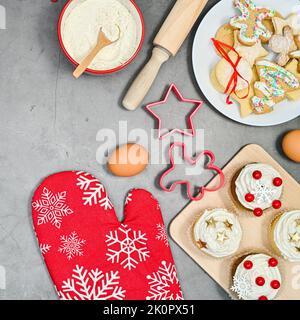 Weihnachtsplätzchen und Cupcakes mit Zutaten zum Backen auf dem Tisch. Flach liegend Stockfoto