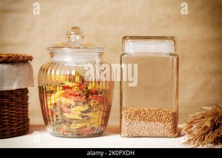 Buchweizen und bunte Pasta auf einem gemütlichen Küchentisch. Küchengeräte und Kochen Stockfoto