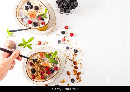 Die Hand einer Frau hält einen Löffel gefüllt mit köstlichem hausgemachtem, gesundem Müsli. Gesundes, sauberes Essen. Fitness. Draufsicht Stockfoto