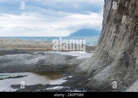 Küste der Insel Kunashir am Kap Stolbchaty mit Basalt-säulenigen Felsen bei bewölktem Wetter Stockfoto