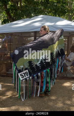 In voller Länge Porträt eines Mitglieds der indianischen Mohegan-Indianer, das einen handgefertigten, gefransten Schal trägt. Beim Shinnecock Powwow 2022. Stockfoto