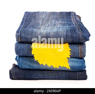 Der Stapel der Jeans-Kleidung und die Form - das gelbe Herbstblatt Stockfoto