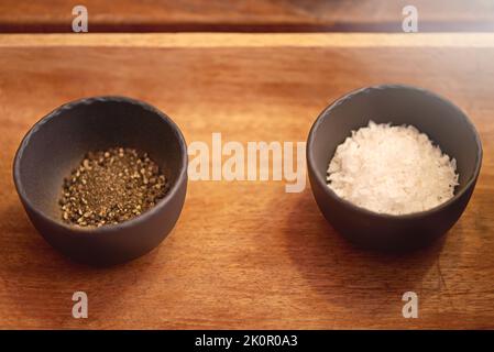 Salz und Pfeffer immer besser, wenn sie zusammen waren. Salz und Pfeffer in Schüsseln auf einer Tischplatte. Stockfoto