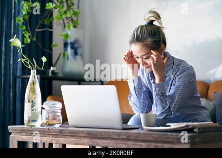 Reife professionelle asiatische Geschäftsfrau, die von zu Hause aus arbeitet, scheint müde und erschöpft zu sein Stockfoto