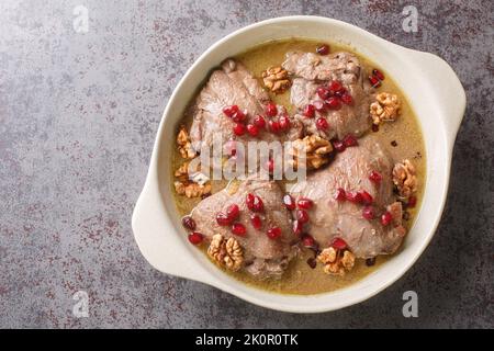 Khoreh Fesenjan zartes Huhn wird in einer Walnussgranatapfelsauce in einer Pfanne auf dem Tisch in der Nähe gekocht. Horizontale Draufsicht von oben Stockfoto