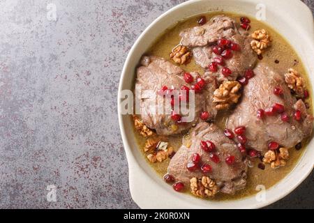 Köstlicher Hähncheneintopf in Granatapfel-Walnusssauce in Nahaufnahme auf einem Teller auf dem Tisch. Horizontale Draufsicht von oben Stockfoto