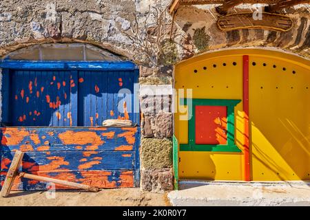 Bunte blaue, gelbe Bootstüren, Klima Fischerdorf, Griechenland. Bemalte und verwitterte Holztüren, weiß getünchte Wände. Stockfoto