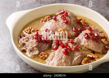 Köstlicher Hähncheneintopf in Granatapfel-Walnusssauce in Nahaufnahme auf einem Teller auf dem Tisch. Horizontal Stockfoto