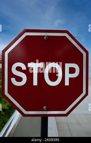 Ein Stoppschild in der Straße mit blauem Himmel Hintergrund Stockfoto