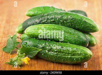 Frische Gurken mit grünen Blättern auf Holzgrund Stockfoto