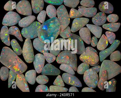 Australische Opal-Edelsteine, aufgenommen auf einem schwarzen Hintergrund, um die wunderschöne Farbe und das Muster dieses Natursteins hervorzuheben. Projekt mit Damien Hirst. Stockfoto