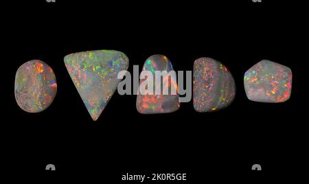 Australische Opal-Edelsteine, aufgenommen auf einem schwarzen Hintergrund, um die wunderschöne Farbe und das Muster dieses Natursteins hervorzuheben. Projekt mit Damien Hirst. Stockfoto