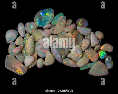 Australische Opal-Edelsteine, aufgenommen auf einem schwarzen Hintergrund, um die wunderschöne Farbe und das Muster dieses Natursteins hervorzuheben. Projekt mit Damien Hirst. Stockfoto