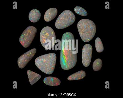 Australische Opal-Edelsteine, aufgenommen auf einem schwarzen Hintergrund, um die wunderschöne Farbe und das Muster dieses Natursteins hervorzuheben. Projekt mit Damien Hirst. Stockfoto