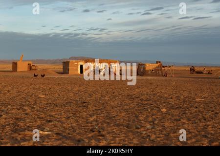 Provinz Errachidia, Marokko - 23. Oktober 2015: Marokkanisches Berberhaus und Berberfamilie in der Nähe der Hausmauer. Sahara-Wüste in Marokko. Stockfoto