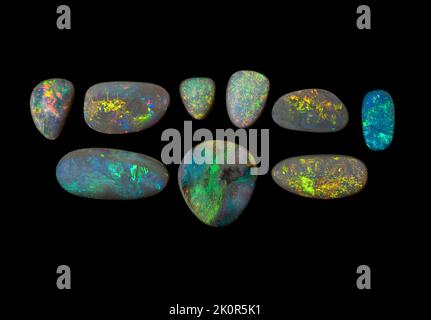 Australische Opal-Edelsteine, aufgenommen auf einem schwarzen Hintergrund, um die wunderschöne Farbe und das Muster dieses Natursteins hervorzuheben. Projekt mit Damien Hirst. Stockfoto