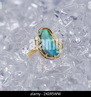 Australischer Queensland Boulder Opal in gelbem Goldring auf Eiswürfeln dargestellt. Stockfoto