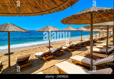 Reihen von Sonnenschirmen und Sonnenliegen bereit für Touristen am Sandstrand. Sommerurlaub, Sonnenbaden, schwimmen, entspannen, blauer Himmel, Meer, Strand Stockfoto