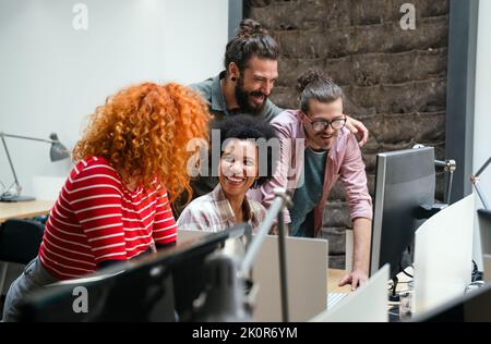 Lächelnde Gruppe von verschiedenen Geschäftsleuten, die gemeinsam über den Papierkram gehen und im Büro des Unternehmens arbeiten Stockfoto