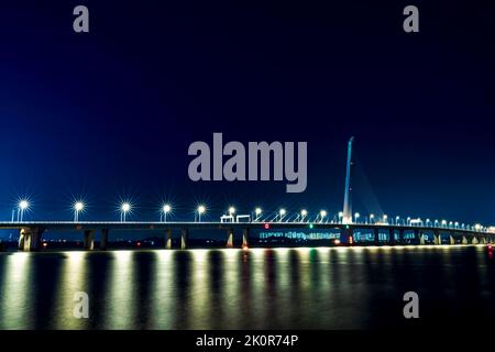 Die beleuchtete Shenzhen Bay Bridge auf blauem Himmel Hintergrund bei Nacht, Langzeitbelichtung Stockfoto