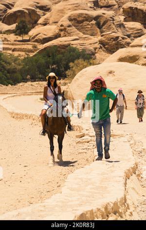 06.18.2022. Petra Canyon, Jordanien. Ein Einheimischer, der ein Pferd mit einem Touristen auf dem Pferd führt. Hochwertige Fotos Stockfoto