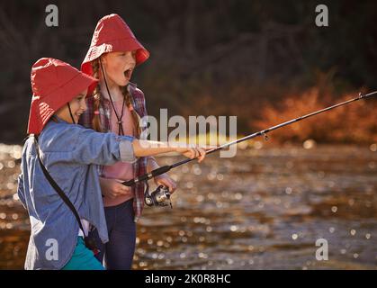 Oh mein Gott, seine riesige. Zwei junge Mädchen, die an einem Fluss fischen. Stockfoto