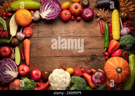 Rahmen aus frischem Obst und Gemüse auf einem hölzernen Hintergrund. Herbsternte und vegane Rezepte für gesunde Lebensmittel Stockfoto