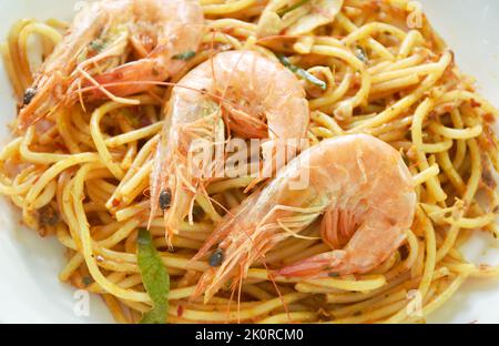 Würzig gebratene Spaghetti-Garnelen mit Chili und Basilikum in tom-Yum-Sauce auf dem Teller essen paar frischen Gemüsesalat Stockfoto