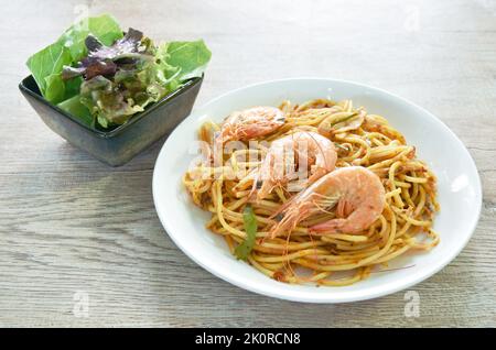 Würzig gebratene Spaghetti-Garnelen mit Chili und Basilikum in tom-Yum-Sauce auf dem Teller essen paar frischen Gemüsesalat Stockfoto