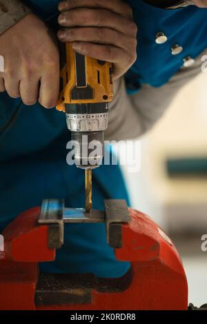 Techniker Arbeiter Hände machen ein Loch in einem Stück Metall mit Bohrer Stockfoto