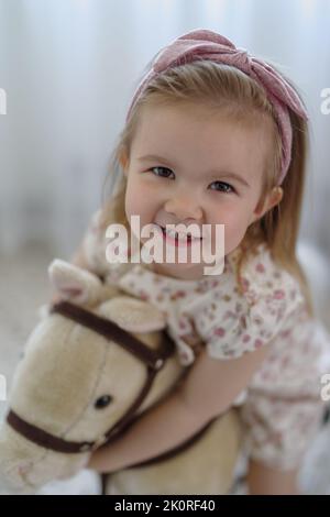 Nettes kleines Mädchen zu Hause spielen, Reiten Wippe Pferd Spielzeug Stockfoto