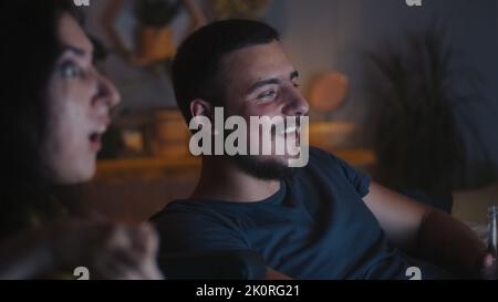 Frau mit einer Behinderung und Mann jubeln und diskutieren Film, während sie es im Fernsehen zusammen zu Hause am Abend Stockfoto
