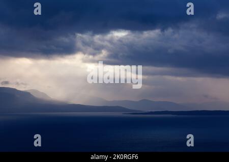 September und Sonnenstrahlen passieren regnerische Wolken. See auf dieser Seite und Berg im Hintergrund. Stockfoto