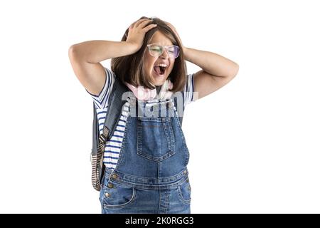 Schulmädchen mit Rucksack und Brille hält sie mit beiden Händen laut schreiend. Stockfoto