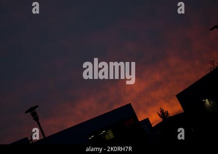 Feuriger Sonnenuntergang über industrieller Silhouette. Angewinkelter Horizont. Stockfoto