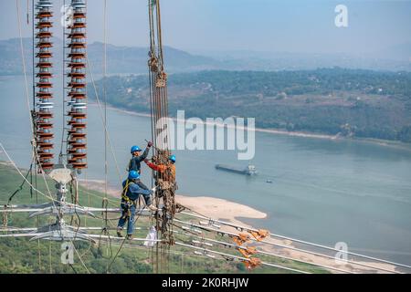 (220913) -- CHONGQING, 13. September 2022 (Xinhua) -- Techniker arbeiten während des Stromverdrahtungsbetriebs über den Yangtze-Fluss für das 800 kv-Ultrahochspannungs-Gleichstrom-Übertragungsleitungsprojekt (UHGÜ) in der Region Chongqing im Südwesten Chinas (Chongqing, 13. September 2022). Nach einer 13-tägigen Kampagne wurde am Dienstag der über den Jangtse-Fluss verdrahtungsbetrieb für das 800-kv-Ultrahochspannungs-Gleichstrom-Übertragungsleitungsprojekt (UHGÜ) in Baihetan-Zhejiang erfolgreich abgeschlossen. Die 2.140 Kilometer lange Strecke, deren Bau im Oktober 2021 begann, schlängelt sich durch Sichuan, Chongqing, Stockfoto