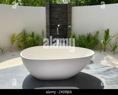 Blick auf eine große ovale Badewanne in einem offenen Duschbad in einer luxuriösen Villa mit Meerblick auf den Malediven. Stockfoto