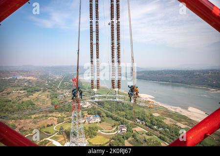 (220913) -- CHONGQING, 13. September 2022 (Xinhua) -- Techniker arbeiten während des Stromverdrahtungsbetriebs über den Yangtze-Fluss für das 800 kv-Ultrahochspannungs-Gleichstrom-Übertragungsleitungsprojekt (UHGÜ) in der Region Chongqing im Südwesten Chinas (Chongqing, 13. September 2022). Nach einer 13-tägigen Kampagne wurde am Dienstag der über den Jangtse-Fluss verdrahtungsbetrieb für das 800-kv-Ultrahochspannungs-Gleichstrom-Übertragungsleitungsprojekt (UHGÜ) in Baihetan-Zhejiang erfolgreich abgeschlossen. Die 2.140 Kilometer lange Strecke, deren Bau im Oktober 2021 begann, schlängelt sich durch Sichuan, Chongqing, Stockfoto