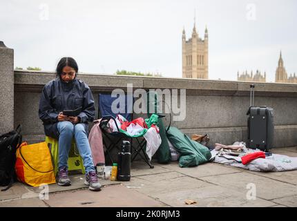 London, Großbritannien. 13. September 2022. Vanessa sitzt gegenüber dem Palast von Westminster an der Spitze der Schlange, die zu den Ersten gehört, die sich mit Königin Elizabeth II. Am ausgestellten Sarg in der Westminster Hall übereingeknotet haben. Die britische Königin Elizabeth II. Starb am 08. September 2022 im Alter von 96 Jahren. Am 14. September wird ihr Sarg in einer öffentlichen Prozession durch die Mall vom Buckingham Palace zum Parlament gebracht, wo er für mehrere Tage in der Westminster Hall verlegt wird. Quelle: Christian Charisius/dpa/Alamy Live News Stockfoto