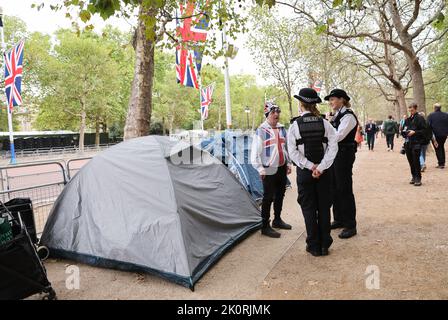 London, Großbritannien. 13. September 2022. Zwei Polizistinnen sprechen mit John Loughrey (l) aus London neben seinem Zelt auf der Straße „The Mall“ vor dem Buckingham Palace. Die britische Königin Elizabeth II. Starb am 8. September 2022 im Alter von 96 Jahren. Am 14. September wird ihr Sarg in einer öffentlichen Prozession über die Mall vom Buckingham Palace zur Westminster Hall gebracht. Quelle: Christian Charisius/dpa/Alamy Live News Stockfoto