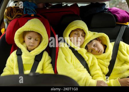 Drei Jungen auf Autositzen, unterwegs im Auto, schlafen, während sie in den Urlaub fahren Stockfoto