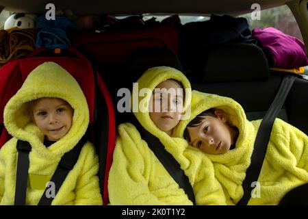 Drei Jungen auf Autositzen, unterwegs im Auto, mit Blick auf die Kamera, während sie in den Urlaub fahren Stockfoto