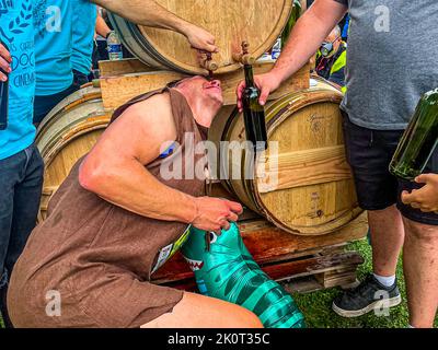 Der Marathon des Chateaux du Medoc ist berühmt für seinen Rotwein unterwegs. Der steinzeitliche Mann Fred Feuerstein scheint einen zvilisierten Rotwein aus einem Glas nicht zu mögen. Er hängt am liebsten direkt unter dem Holzfass von Château Larose Trintaudon Stockfoto