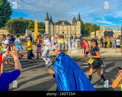 Das farbenfrohe Hauptfeld vor einer historischen Kulisse. Auf der Marathonstrecke passieren die Teilnehmer des Marathon des Chateaux du Medoc 36. insgesamt 25 Weingüter. Oft geht es durch die Mitte des Schlosses und es wird Rotwein und Wasser angeboten Stockfoto